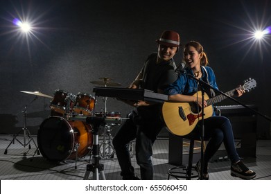 Musician duo band singing a song and playing music instrument with Fellow band musicians on black background with spot light and lens flare, musical concept. - Powered by Shutterstock