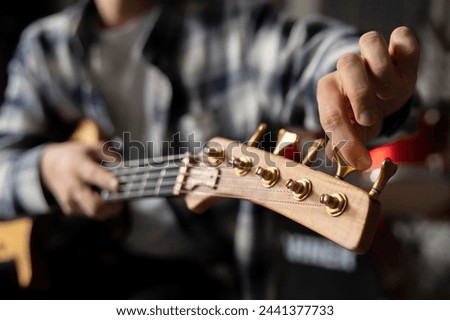 Musician Fine-Tuning Acoustic Guitar Strings in a Dimly Lit Room of music studio