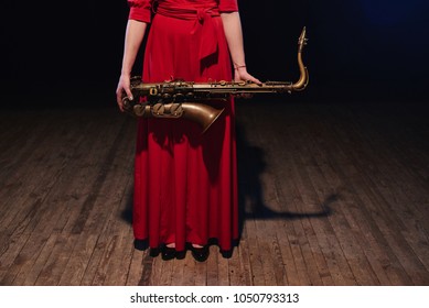 Musician girl in a red dress with a saxophone on stage - Shutterstock ID 1050793313
