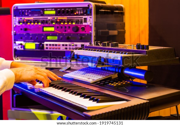 musician hands playing electric piano\
with soundmodule background in recording\
studio