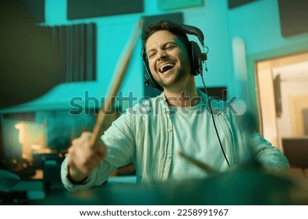 Musician, headphones and man drummer playing in a recording studio for production of a song. Musical artist, drums and male with a passion for music with a percussion instrument for entertainment.