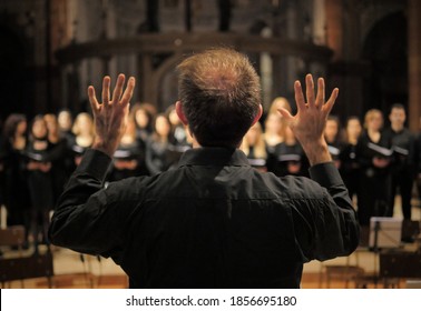 Musician leads a choir during a concert in a cathedral. Musical rehearsals before the concert during the Christmas period. Life of musicians and classic holy music. - Powered by Shutterstock