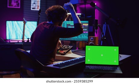 Musician mixing and mastering sounds at home studio with electronic console and soundboard, creating modern tunes. Sound engineer producing audio tracks with greenscreen on tablet. Camera B. - Powered by Shutterstock