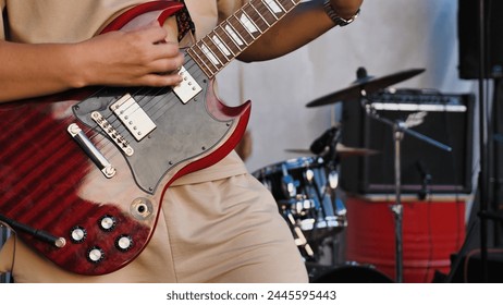 A musician, passionately strumming an electric guitar, on a concert stage illuminated by spotlights, stage equipment in the background. The atmosphere is filled with the energy of live music - Powered by Shutterstock