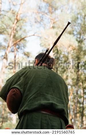 A musician playing the bagpipes at an outdoor music folk festival. Rear view, selective focus.
