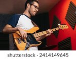 musician playing the bass guitar in a music venue. the artist focuses on producing deep and resonant notes that fill the rehearsal space.