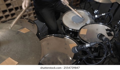 musician playing a drum set in a professional recording studio with acoustic paneling and recording equipment in the background. The scene captures the essence of live music production and creativity. - Powered by Shutterstock