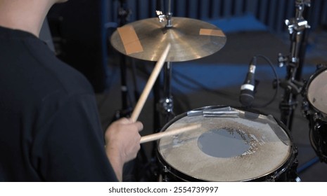 musician playing a drum set in a professional recording studio with acoustic paneling and recording equipment in the background. The scene captures the essence of live music production and creativity. - Powered by Shutterstock