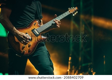 Musician playing guitar while performing on a concert on a festival