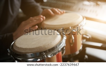 Musician playing hand Bongo Drums indoors closeup. Man with traditional ethnic folk music instrument