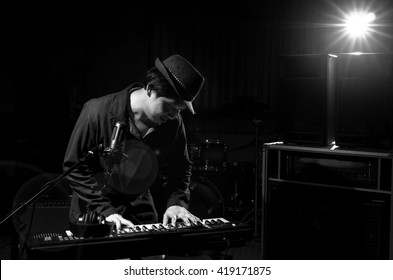 Musician playing keyboard with music instrument and lens flare from spot light on dark background, Musician concept - Powered by Shutterstock