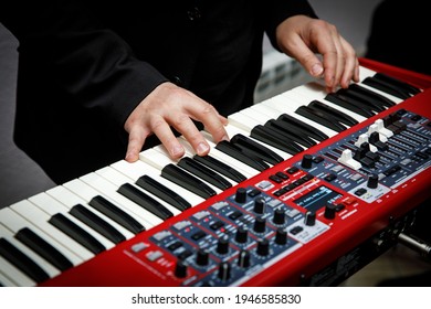 Musician playing on red electric keyboards. Fingers on keys, close-up