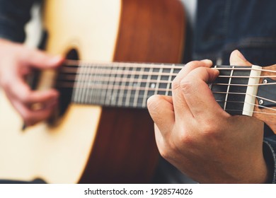 musician playing strum acoustic guitar.	