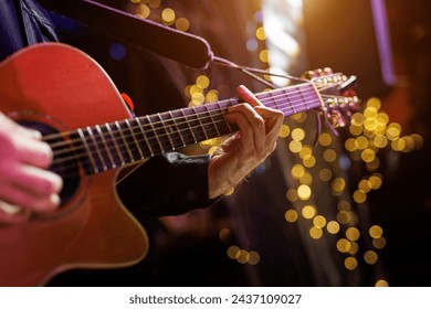 A musician plays a chord on an acoustic guitar during a performance. - Powered by Shutterstock