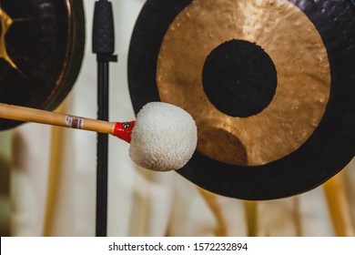 A musician strikes a gong with a mallet