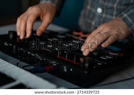Musician using a loop station and MIDI pad controller with a keyboard in the background. Concept of modern music production, beatmaking, sound recording, and electronic performance.