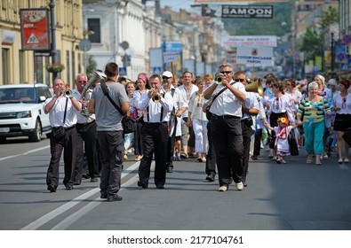 Musicians From A Brass Orchestra Walking Down The Street Playing Music, Crowd Of People In Ukrainian National Embroidered Shirts Behind. Celebrating Day Of Dnipro River. July 7,2019. Kyiv, Ukraine