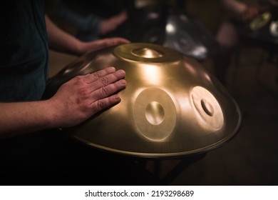 A musician's hand playing the handpan with other people. Handpan is a term for a group of musical instruments that are classified as a subset of the steelpan.  - Shutterstock ID 2193298689