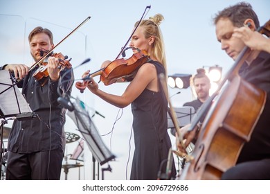 Musicians playing classical instrumental music on outdoor stage - Shutterstock ID 2096729686