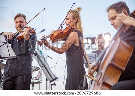 Musicians playing classical instrumental music on outdoor stage