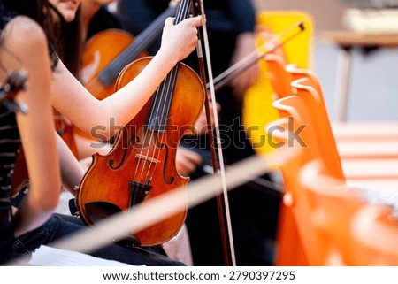 Musicians playing string instruments at a rehearsal. Focus on a violinist with instrument
