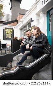 Musicians with smart phone outside bar - Shutterstock ID 2219621119