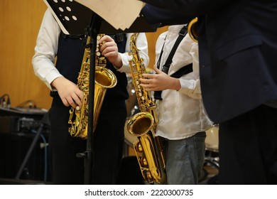 Musicians Young Students Playing The Saxophone Stand In Front Of The Notes In Class In A School Classroom With A Teacher