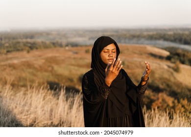 Musim woman praying to Allah. African woman in black robe pray solat