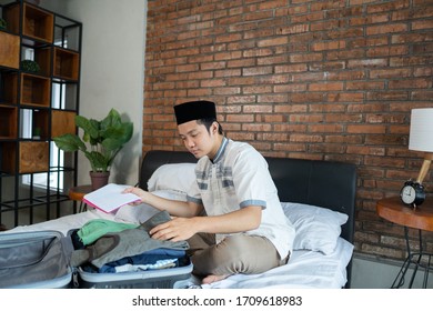 Hombre musulmán asiático sostiene una lista de verificación para el equipaje antes de viajar
