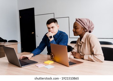 Muslim Black Girl And White Man With Laptop. Multiethnic Couple Work Online Together On Business Project. Working At Home. Surfing Internet