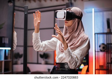 Muslim business woman in VR glasses standing at office room and gesturing with hands. Young female company worker having briefing with modern technology. Concept of people and augmented reality. - Powered by Shutterstock
