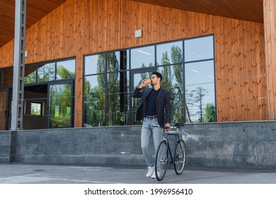 Muslim businessman drinking coffee near bicycle outdoors