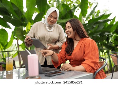 muslim businesswoman discuss about work with her coworker in an outdoor cafe - Powered by Shutterstock