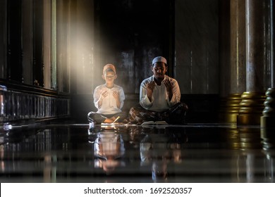 Muslim Children Kid And Old Man Teaching Wearing White Shirts Doing Prayer Reading Book According To The Principles Of Islam.
