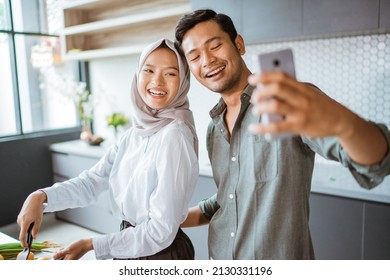 Muslim Couple Cooking Their Food In The Kitchen And Taking Selfie