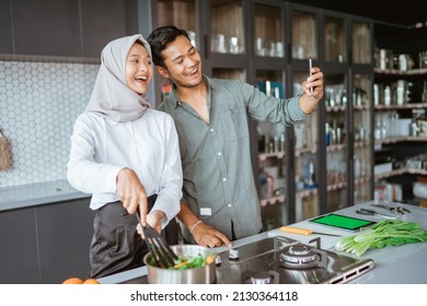 Muslim Couple Cooking Their Food In The Kitchen And Taking Selfie