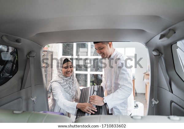 muslim couple packing suitcase in the car trunk\
for holiday
