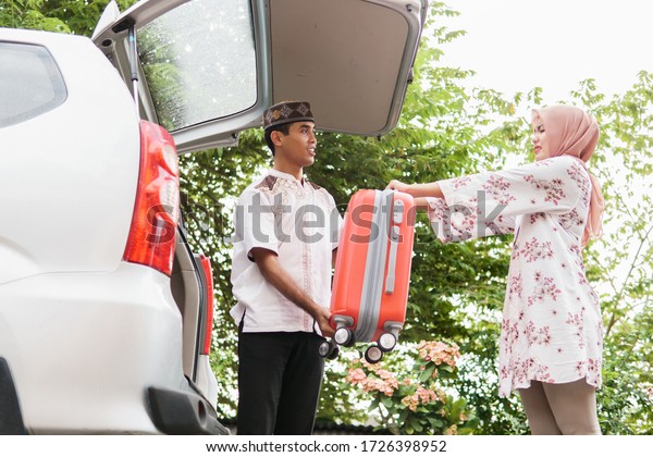 muslim couple packing suitcase in the car trunk\
for holiday
