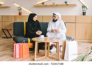muslim couple sitting on sofa in cafe after shopping