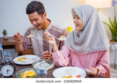 Muslim Couple Wake Up Early To Have Sahur Or Suhur Breakfast For Fasting. Clock At Foreground Showing The Time