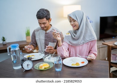 Muslim Couple Wake Up Early To Have Sahur Or Suhur Breakfast For Fasting. Clock At Foreground Showing The Time