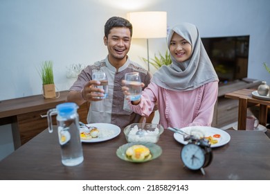 Muslim Couple Wake Up Early To Have Sahur Or Suhur Breakfast For Fasting. Clock At Foreground Showing The Time