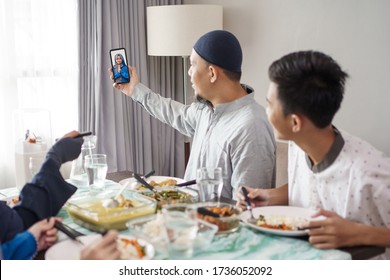 Muslim Family Asian Celebrating Eid Mubarak Having Lunch Together At Home And Make A Phone Call To Other Family