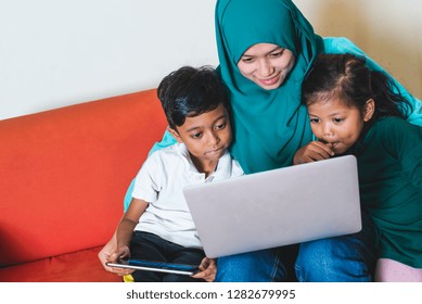 Muslim Family - Single Mum And Children - Happily Watching Movie On A Laptop. Indoor, At Home.