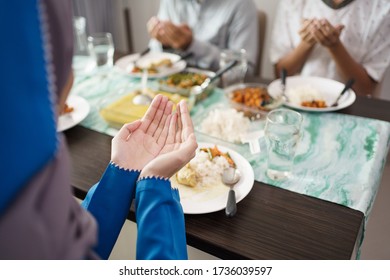 muslim family together pray before meals, a fast breaking meal served on a table - Powered by Shutterstock