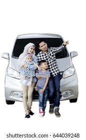 Muslim Family Using A Digital Tablet And Sitting On The Hood Of Their Car While Looking At Something