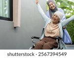 Muslim female doctor caregiver assisting elderly patient in wheelchair, healthcare service, senior care concept, medical support, rehabilitation, health professional with stethoscope providing help