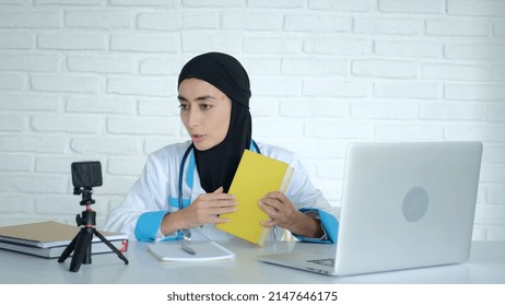 Muslim female doctor teaching at medical university remotely using webcam, online education. A medical college teacher trains future doctors and nurses. A doctor in a black hijab teaches students.