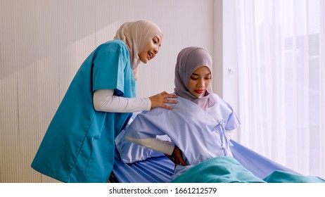 Muslim Female Physiotherapist Taking Care Of Patient At Hospital Room.