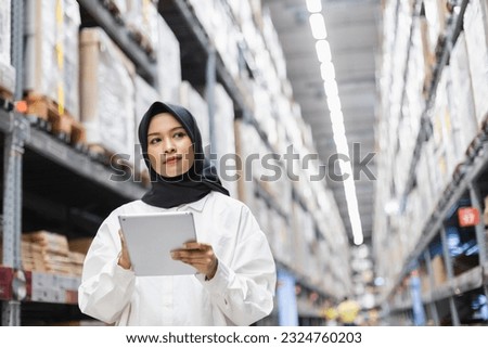 Muslim female wearing hijab warehouse worker holding tablet checks stock on shelf storehouse. businesswoman islamic entrepreneurs rent a warehouse.